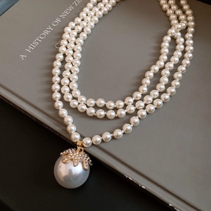 Close-up of three-layer pearl necklace with large pearl pendant on a vintage book