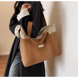 Detail of color-block canvas tote bag showing contrast brown straps and spacious interior