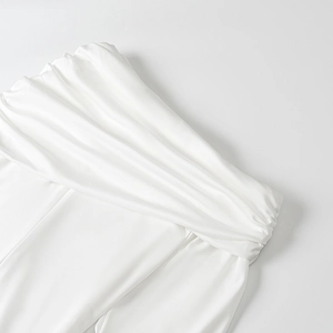 Detail showing the pleated waistline of a white flowy skirt in elegant mesh fabric