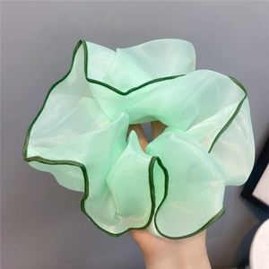 Detail of light green chiffon hair scrunchie with dark green piping and soft texture