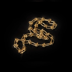 Minimalist 18K gold knot thorn chain necklace displayed on a black background
