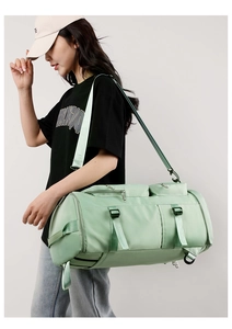 Light green fitness duffel bag shown on model with adjustable straps and zip pockets