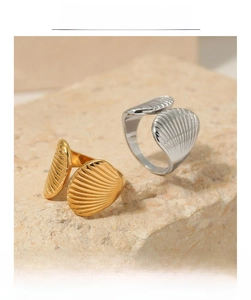 Close-up of gold and silver shell-textured open rings on a stone pedestal