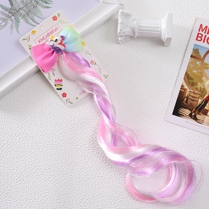 Detail showing rainbow gradient wig hairpiece with unicorn bow clip on display card