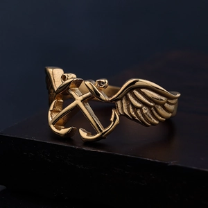 Vintage gold punk style anchor and wings stainless steel ring on a dark stone pedestal