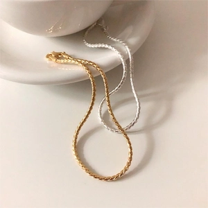 Detail of gold and silver S925 sterling silver twisted rope bracelets on a white ceramic cup