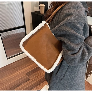 Brown leather tote bag with white faux fur trim styled on a grey woolen coat