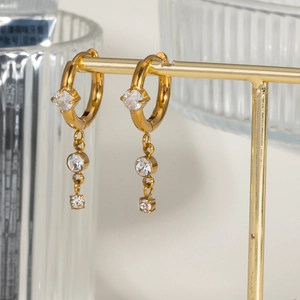 Golden titanium steel hoop earrings with sparkling tassel diamonds on metal display stand