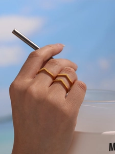 Dual gold V-shaped open rings in polished stainless steel worn for a summer beach look