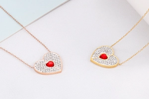 Detail of heart-shaped pendants with red gemstones and crystals in gold and rose gold