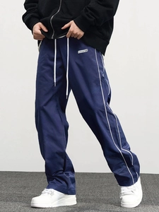 Detail view of navy blue jogger pants with white side stripes and MUSCLEATTACK brand label