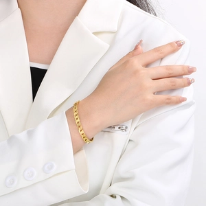 Detailed view of a gold-toned titanium steel Cuban link bracelet on a wrist