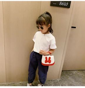 Detail of a white mini handbag with a large red bow handle held by a girl in summer outfit