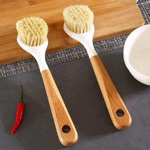 Detail view of kitchen cleaning brushes with wooden handles and dense beige bristles