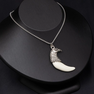 Macro detail of silver eagle head pendant with white wolf tooth on black bust model