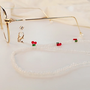Handmade beaded eyewear chain with red cherry charms and gold accents on gold glasses