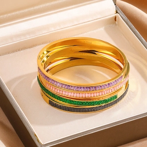Stack of four gold stainless steel bangles with multicolored baguette-cut cubic zirconia
