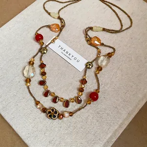 Sautoir bohème multicouche avec perles ambrées rouges et pendentifs floraux en métal