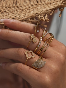 Close-up of golden boho rings set with clover, pearls and zircons on woman's hand