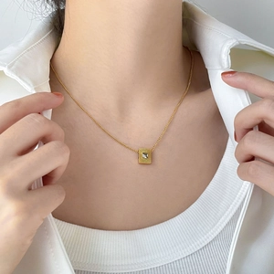Detail of a square geometric pendant with clear zircon on a gold titanium necklace