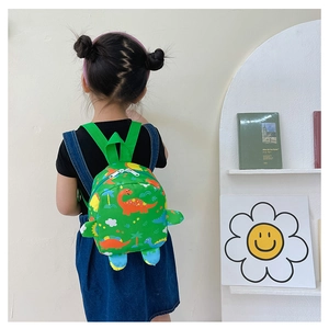 Detail of green kids backpack with cartoon dinosaur pattern worn by a child