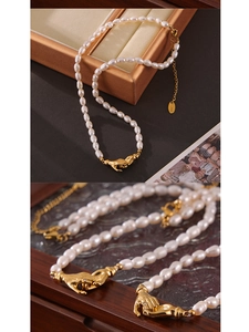Detailed macro view of handshake clasp and baroque pearl on high-gloss necklace