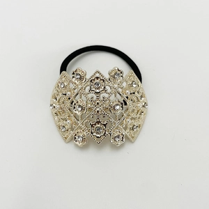 Detailed close-up of golden geometric floral hair tie with rhinestones and white pearls