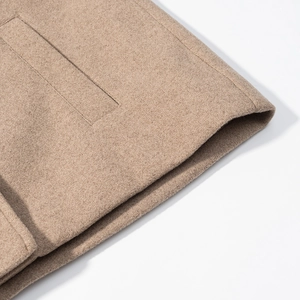 Detail of camel wool coat showing premium stitching and textured fabric on the cuff