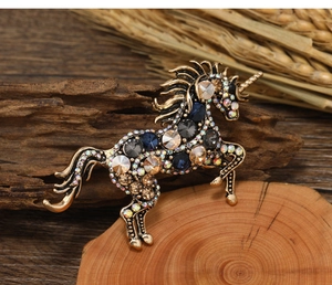 Close-up of vintage unicorn brooch with colorful crystals on a rustic wooden background
