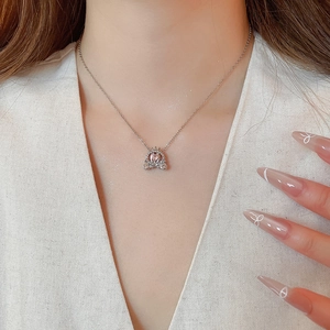 Detail of silver pumpkin carriage necklace with pink gemstone on model neck