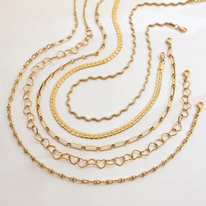 Elegant gold stainless steel necklaces with heart and wave link designs on white background