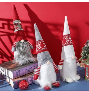 Detailed view of three knitted Christmas gnomes in red, white and grey on art books