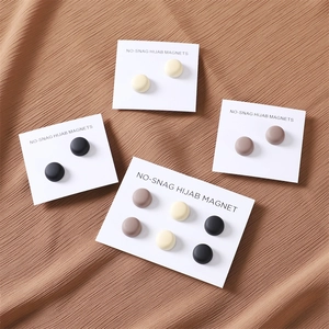 Macro detail of multi-colored no-snag magnetic hijab pins on white cards over fabric