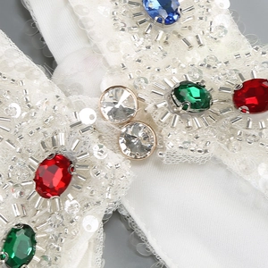 Macro detail of colorful rhinestones and silver beads hand-sewn on white sequined dress