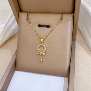 Close-up of titanium necklace with pink teardrop crystal and sparkling bow pendant