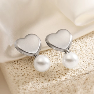 Minimalist silver heart earrings with white pearls on elegant silk and stone background