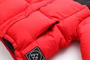 Gros plan de la veste matelassée rouge et noire montrant les détails de la poche latérale