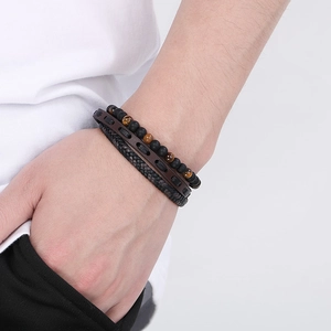 Detail of man wearing multi-layer tiger eye stone beads and brown leather wrap bracelets