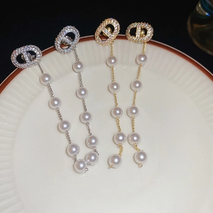 Macro shot of silver and gold zircon tassel earrings with pearls on a white plate