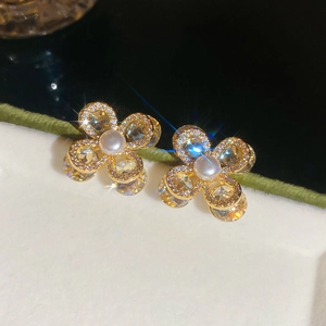 Vue détaillée de boucles d'oreilles fleur dorées avec pétales en cristal et perle