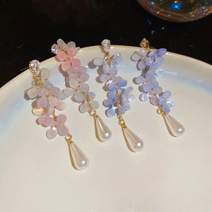Close-up of matte flower earrings with purple gradient petals and teardrop pearl charms