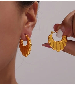 Macro detail of gold-plated U-shaped hoop earrings featuring a vintage textured design