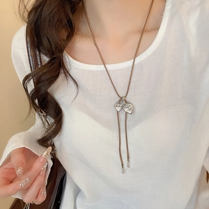 Detail of silver double heart pendant on long brown cord necklace worn by a model