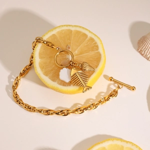 Detail of gold titanium steel bracelet with shell, fishbone, and conch charms on OT clasp