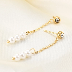Detail of 18K gold pearl tassel earring with crystal stud and long chain design