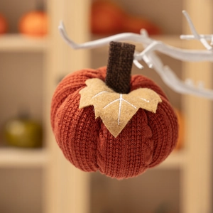 Knitted orange pumpkin ornament with a brown stem for autumn and Thanksgiving home decor