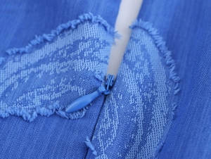 Détail de la fermeture éclair invisible et des franges sur la robe jacquard bleue