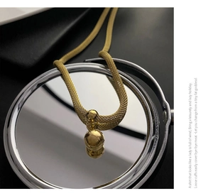 Macro di una collana a maglia intrecciata dorata con ciondolo a sfera lucida su specchio