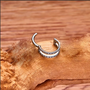 Macro shot of silver F136 titanium double-row zircon hoop earring on wooden texture