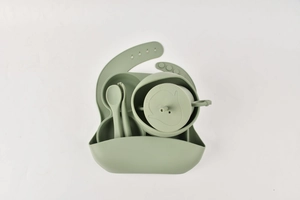 Detailed view of green silicone baby feeding set with bib, bowl, and plate on white background